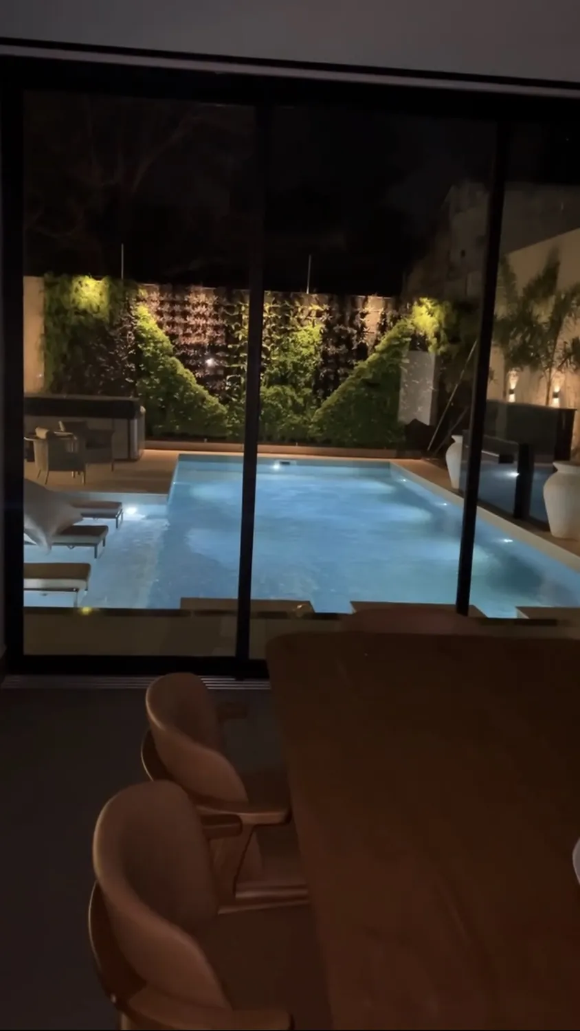 Estar de noche con iluminación de escena y vista a la piscina